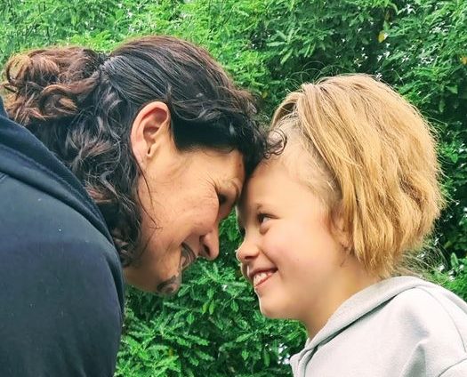A Māori woman giving a hongi to a young blonde child