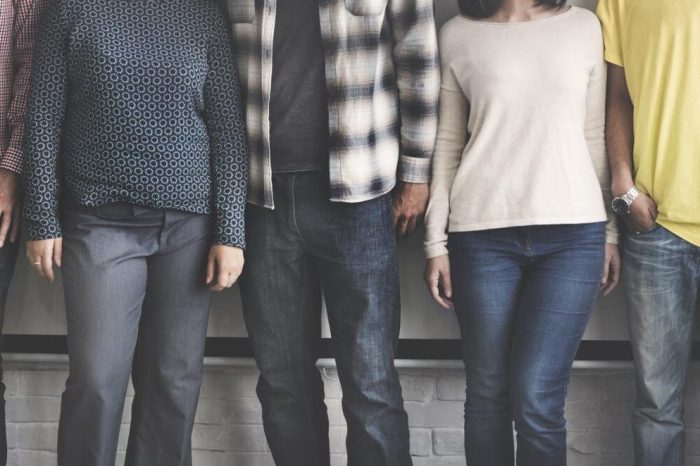 Line of people standing all wearing jeans