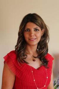 Mahsa Mohaghegh in a red top in front of a brown wall