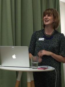 Sarah Hingle in front of a green curtain behind a macbook