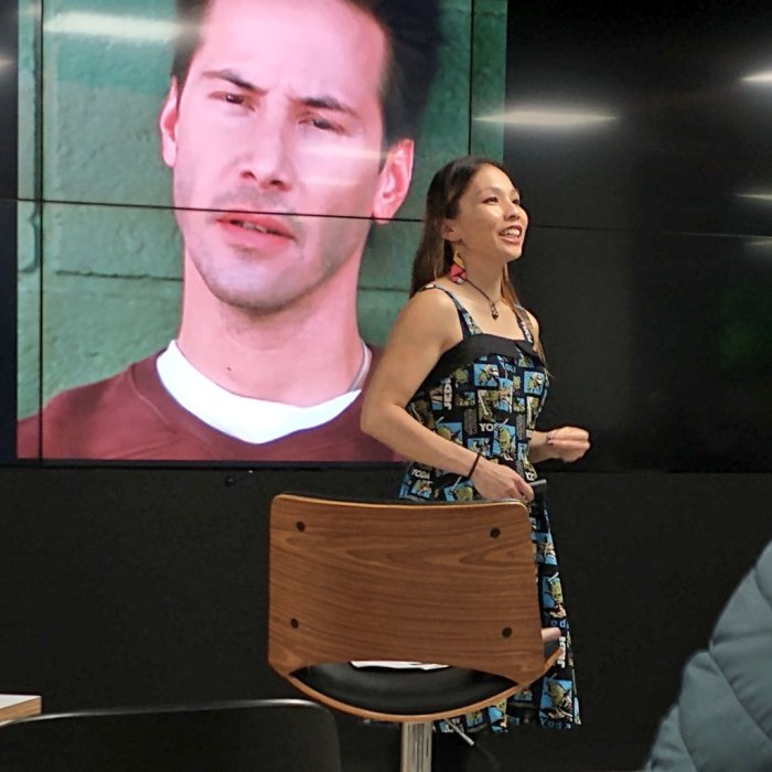 Me in a Yoda dress (Black trim with green and blue squares depicting Yoda) standing in front of a screen with a confused looking Keanu Reeves