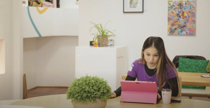 Me, sitting at a table with a pink Surface Pro laptop