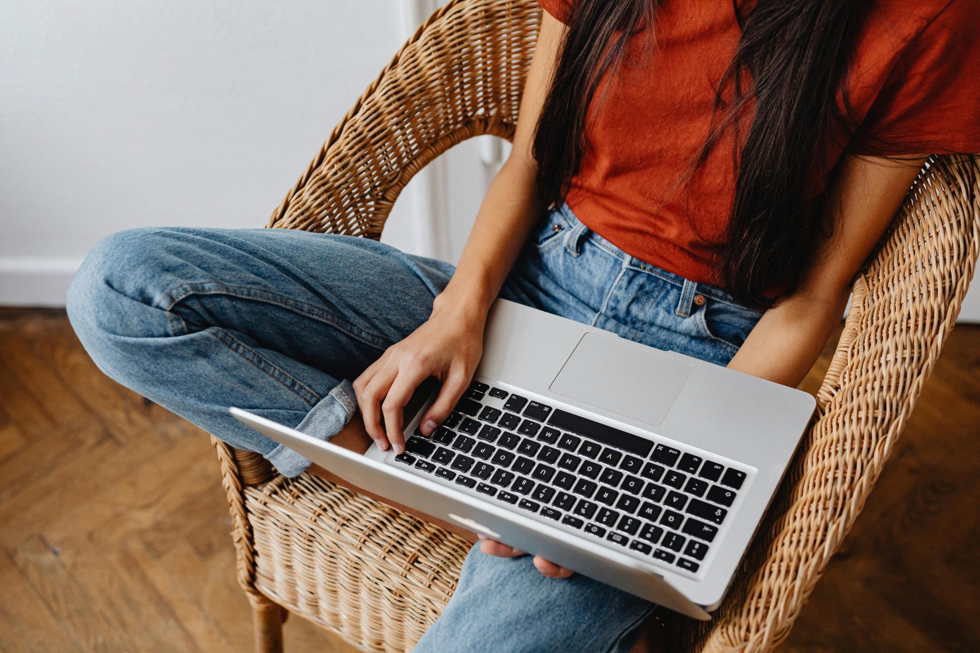 Largely decorative image of a person on a wicker chair using a laptop