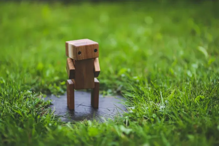 largely decorative image depicting a small robot standing on a small platform in grass