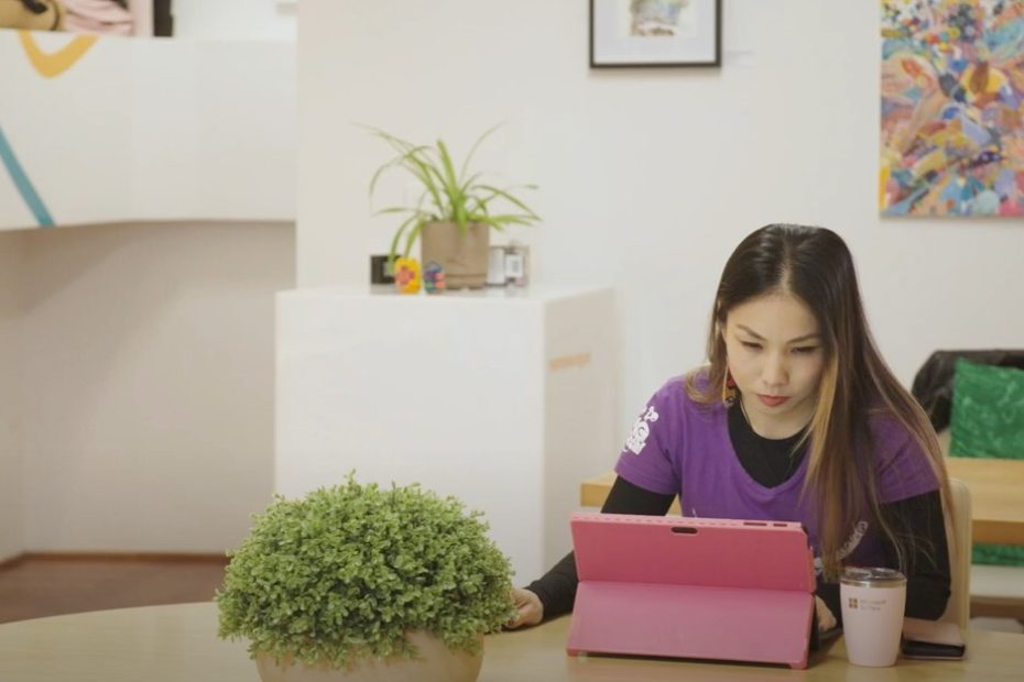 Largely decorative still from the video. It is me sitting at a table surrounded by plants with a pink laptop in front of me